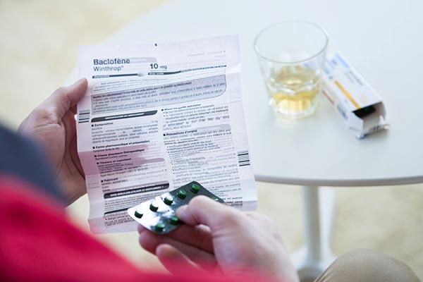 User hold pharmaceutical medication and unfolded instructions-for-use print-out